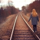 Rear view of a girl walking along railway lines